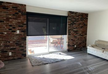 Custom screen shades installed on Malibu living room sliding glass doors leading to a sunlit patio