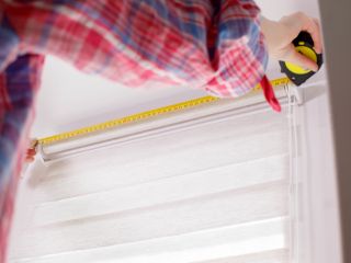 A man takes a mesure for blinds installation in Malibu